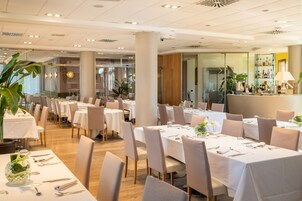 Ein geräumiges Restaurant mit mehreren gedeckten Tischen, großen Fenstern und einer Bar.