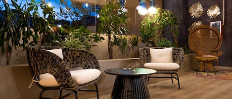 Un espace de détente moderne avec des fauteuils en osier, une table ronde et des lampes suspendues.