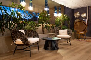 Un área de descanso moderna con sillones de mimbre, una mesa redonda e iluminación colgante.