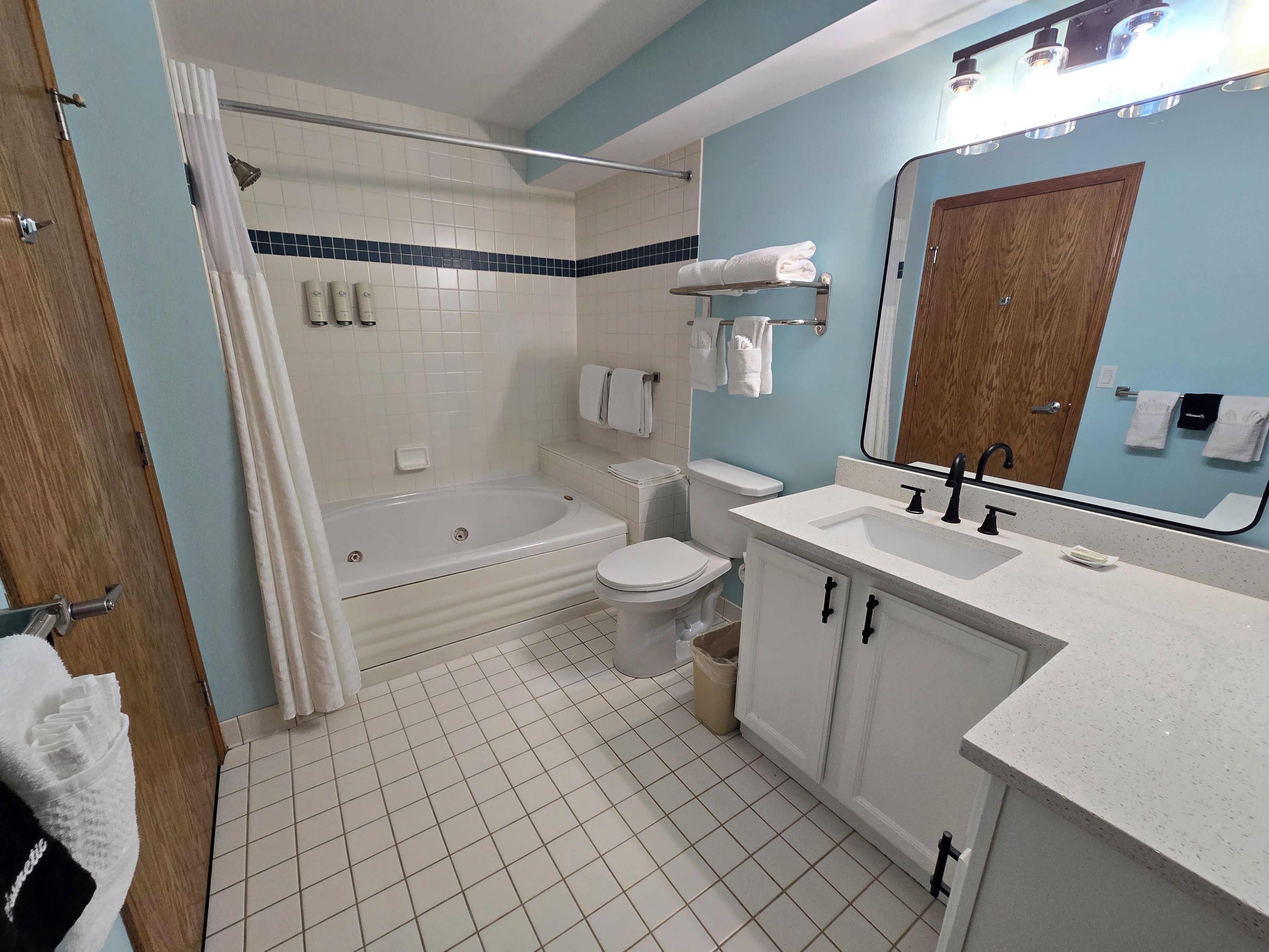 A bathroom with a bathtub, toilet, sink, and a mirror.