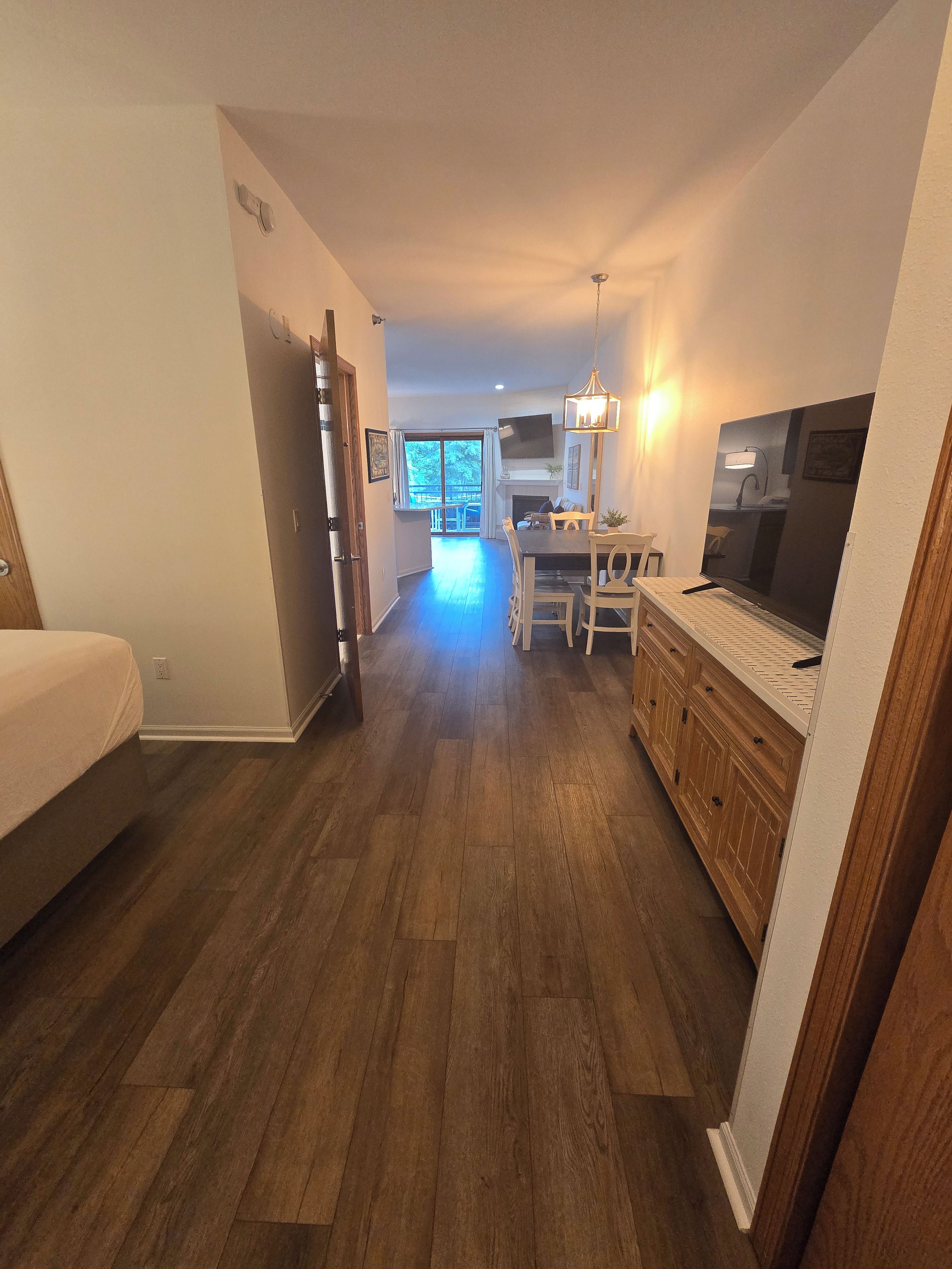 Une pièce spacieuse avec un plancher en bois, un coin repas comprenant une table et des chaises, un téléviseur et une cheminée.