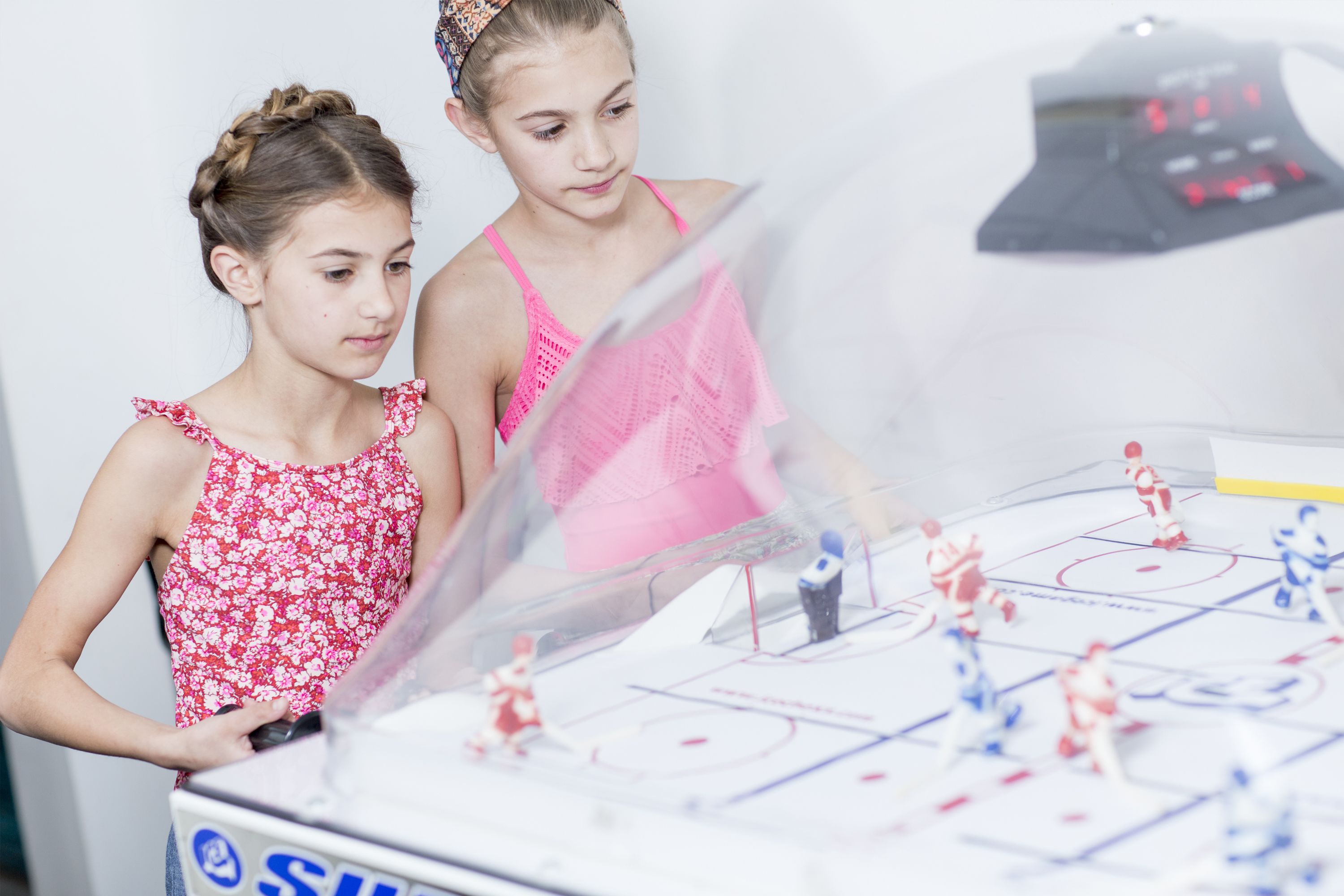 Two children playing a game on a table with a hockey theme.