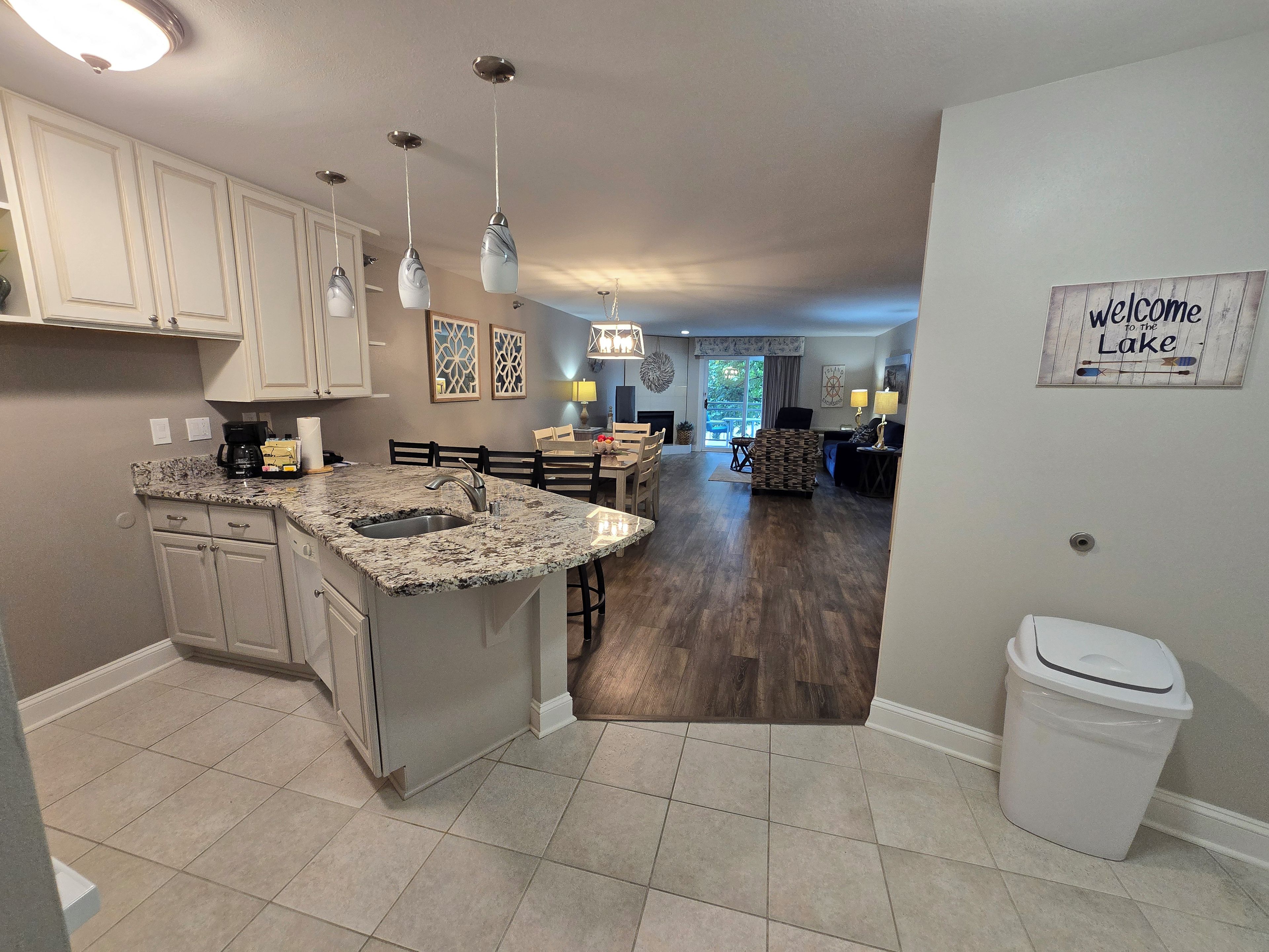 A kitchen with granite countertops, a sink, and a dining area with a table and chairs.