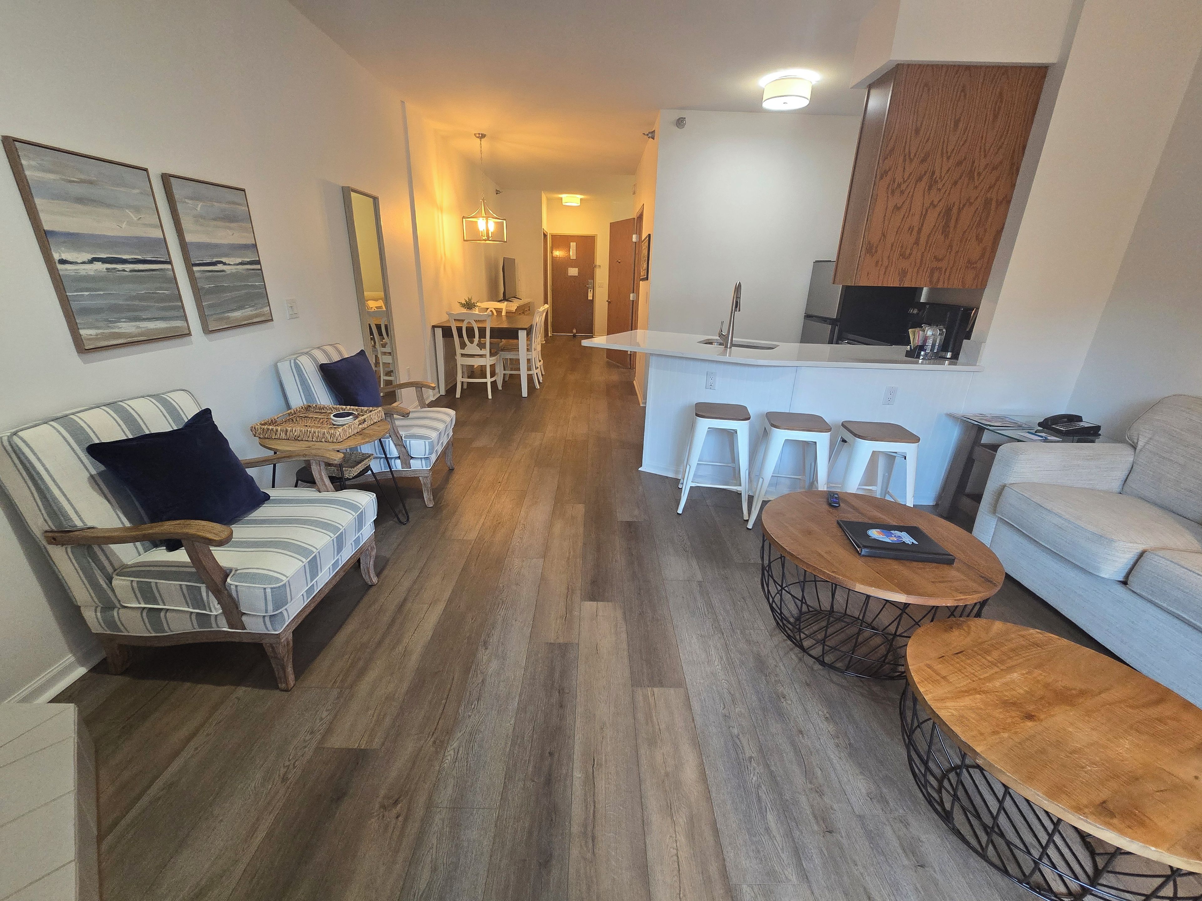 A modern living room with a sofa, armchairs, a coffee table, and a dining area with chairs and a table.
