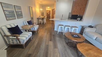 Una sala de estar moderna con un sofá, sillones, una mesa de centro y un comedor con sillas y una mesa.