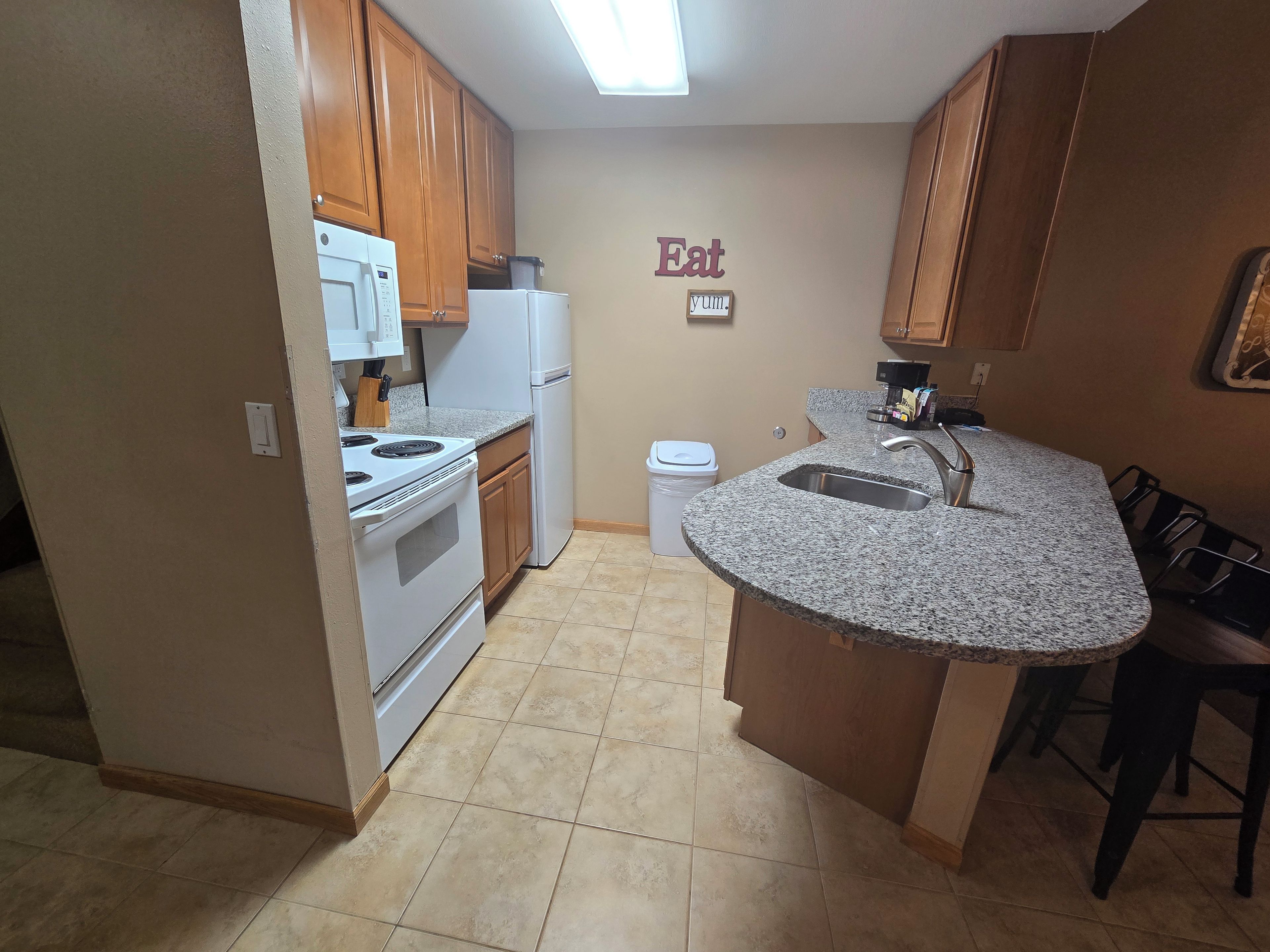 A kitchen with wooden cabinets, a white stove, a sink, and a countertop.