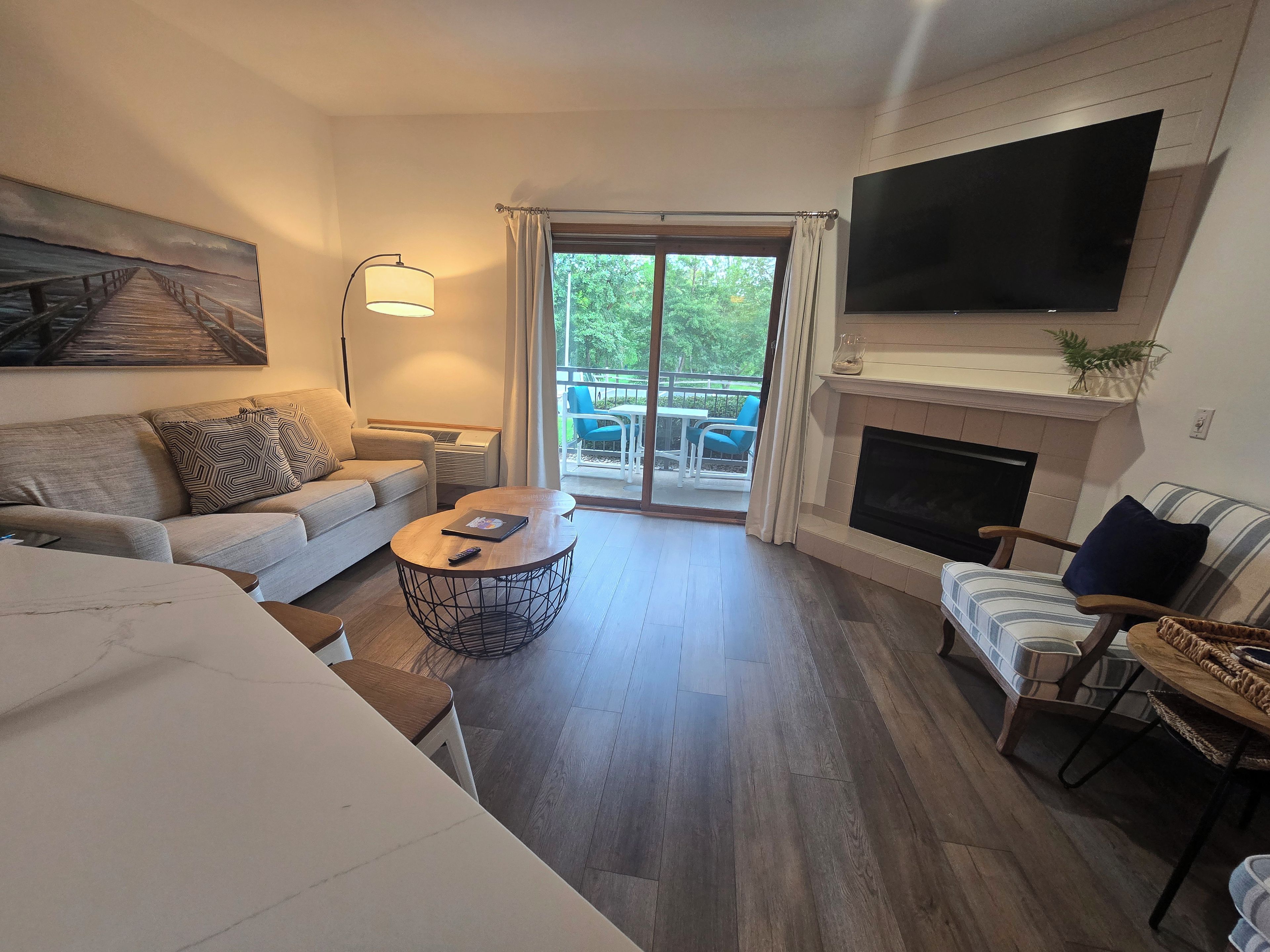 A living room with a sofa, a coffee table, a fireplace, and a TV mounted on the wall.