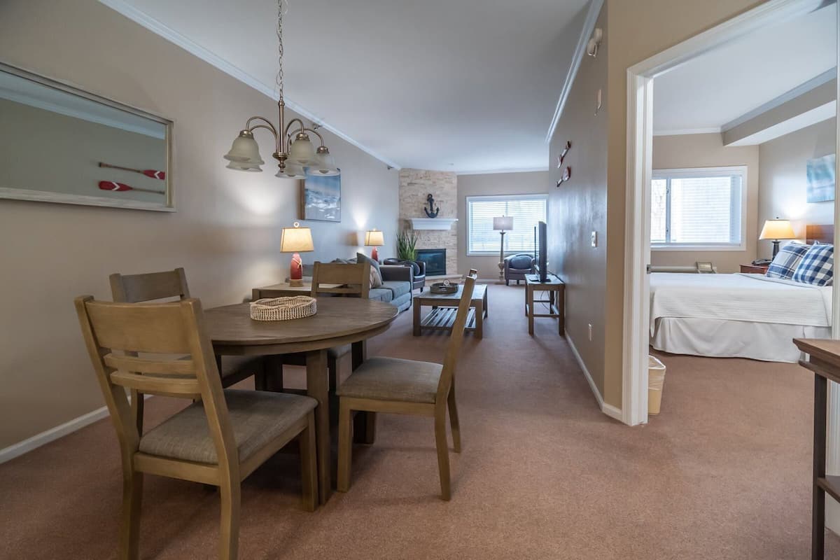 Une pièce confortable avec une table à manger, des chaises, une cheminée, un lit et un téléviseur.