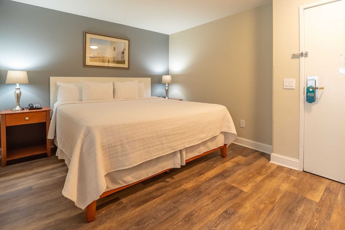 Une chambre à coucher comprenant un lit, des tables de chevet, une porte et un tableau accroché au mur.