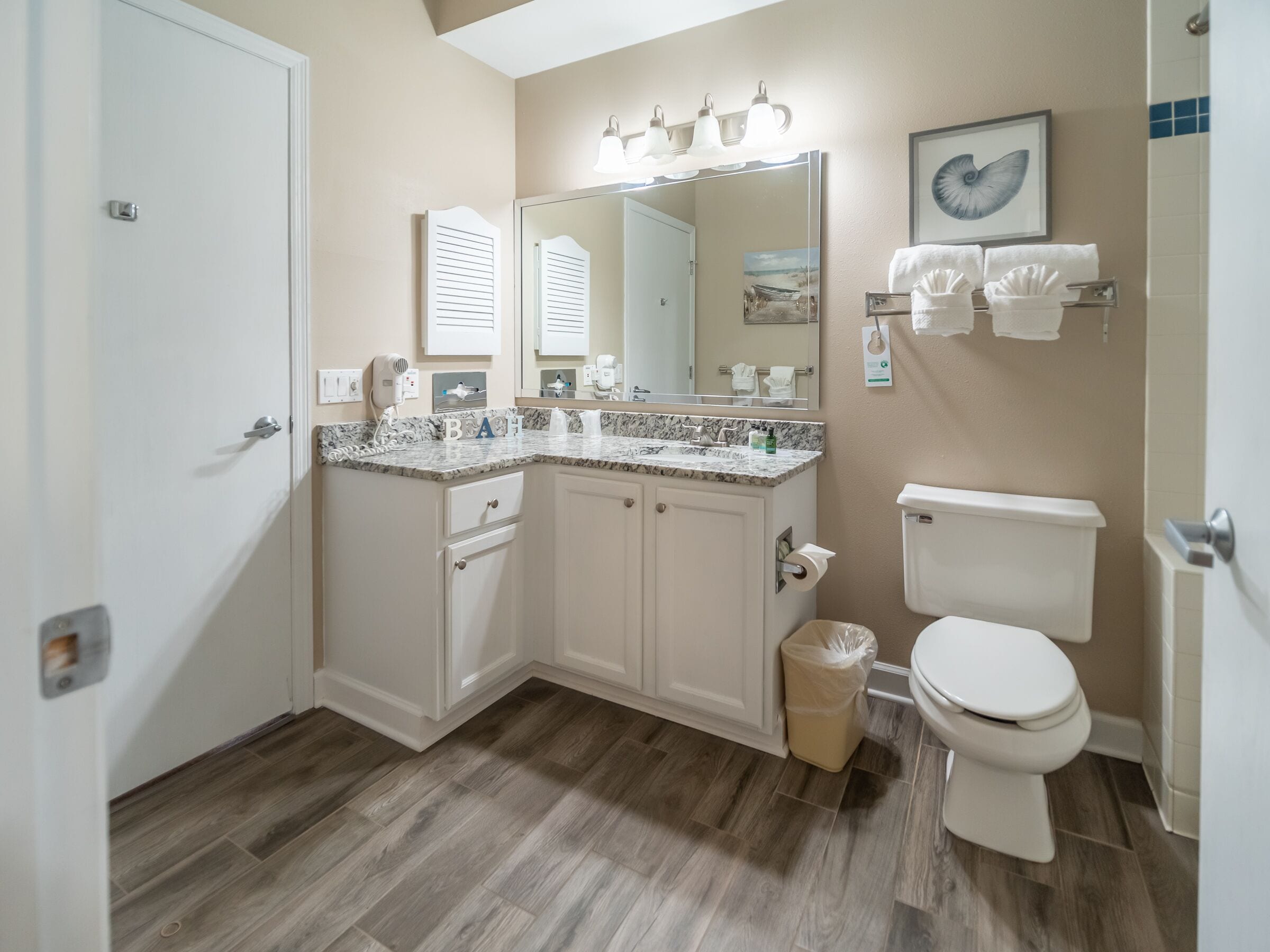 A bathroom with a vanity, sink, mirror, and toilet.