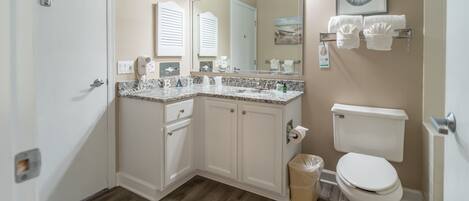 A bathroom with a vanity, sink, mirror, and toilet.