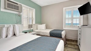 Un dormitorio con dos camas, televisión, ventana con vistas y aire acondicionado de pared.