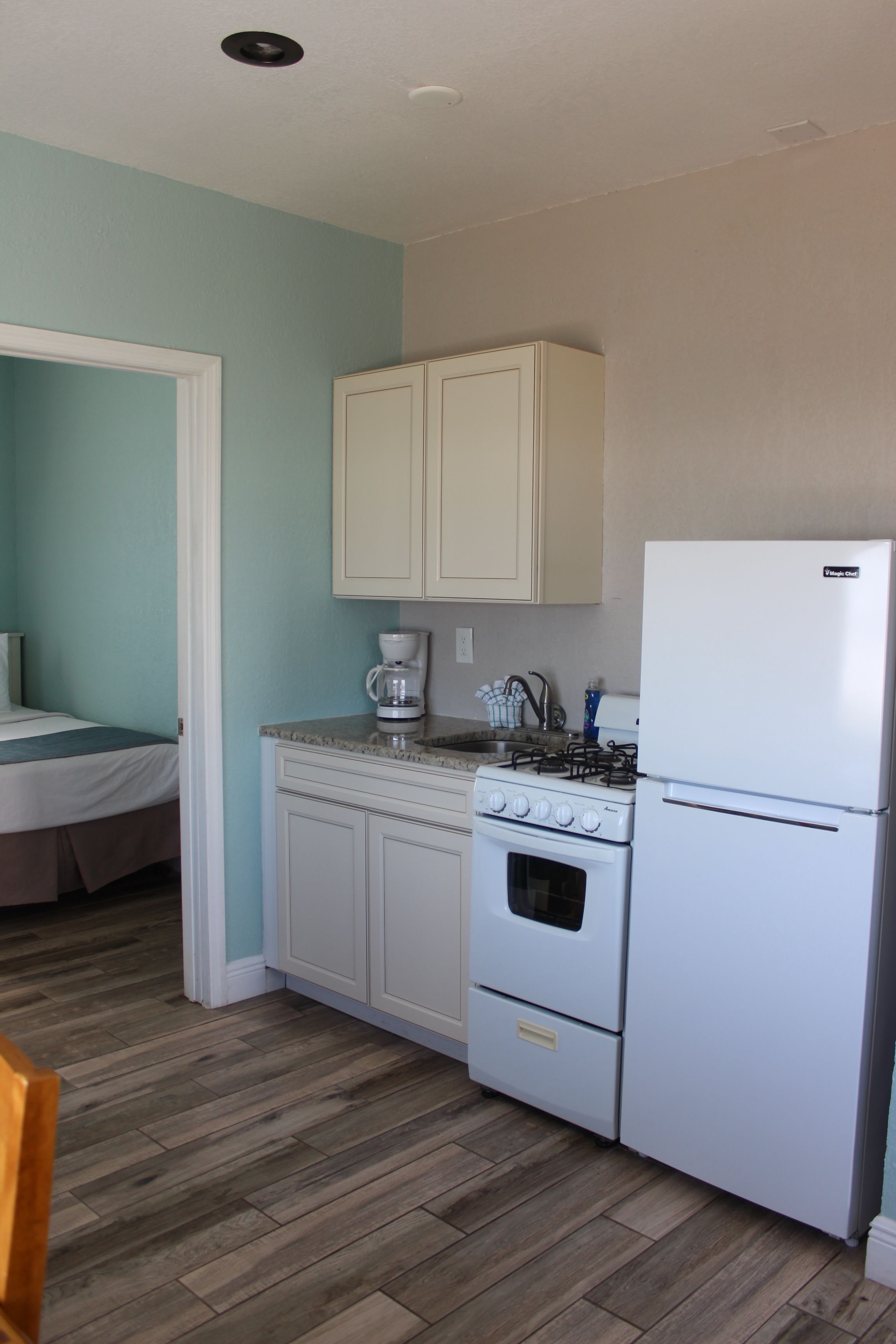 A compact kitchen with white cabinets, a stove, and a refrigerator.