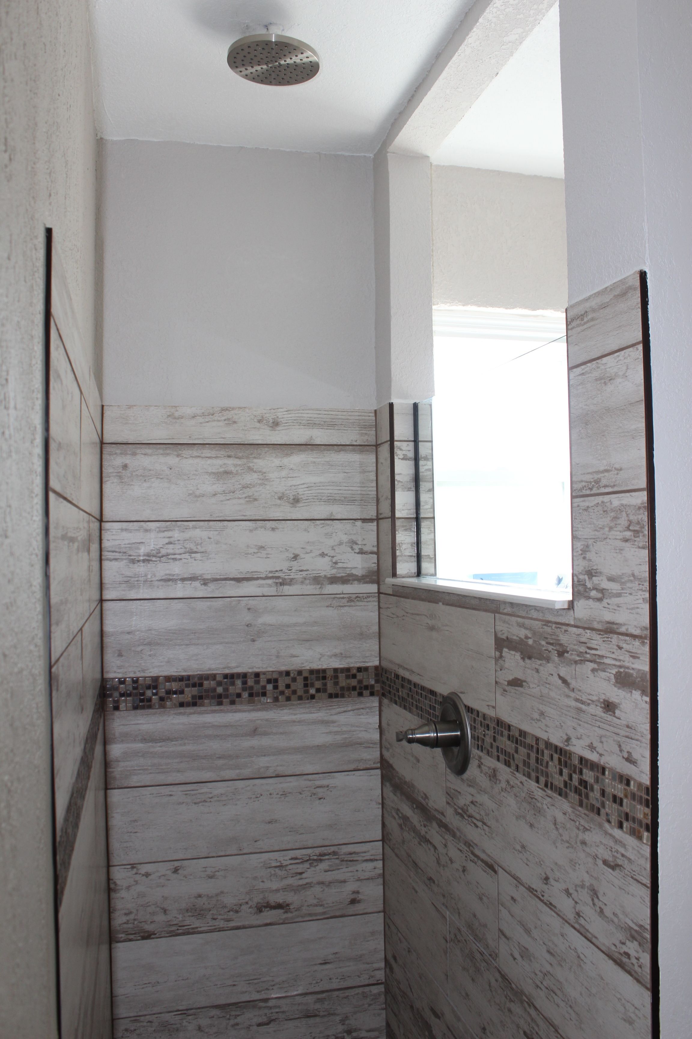 Eine Dusche mit Holzvertäfelung und einem kleinen Fenster.