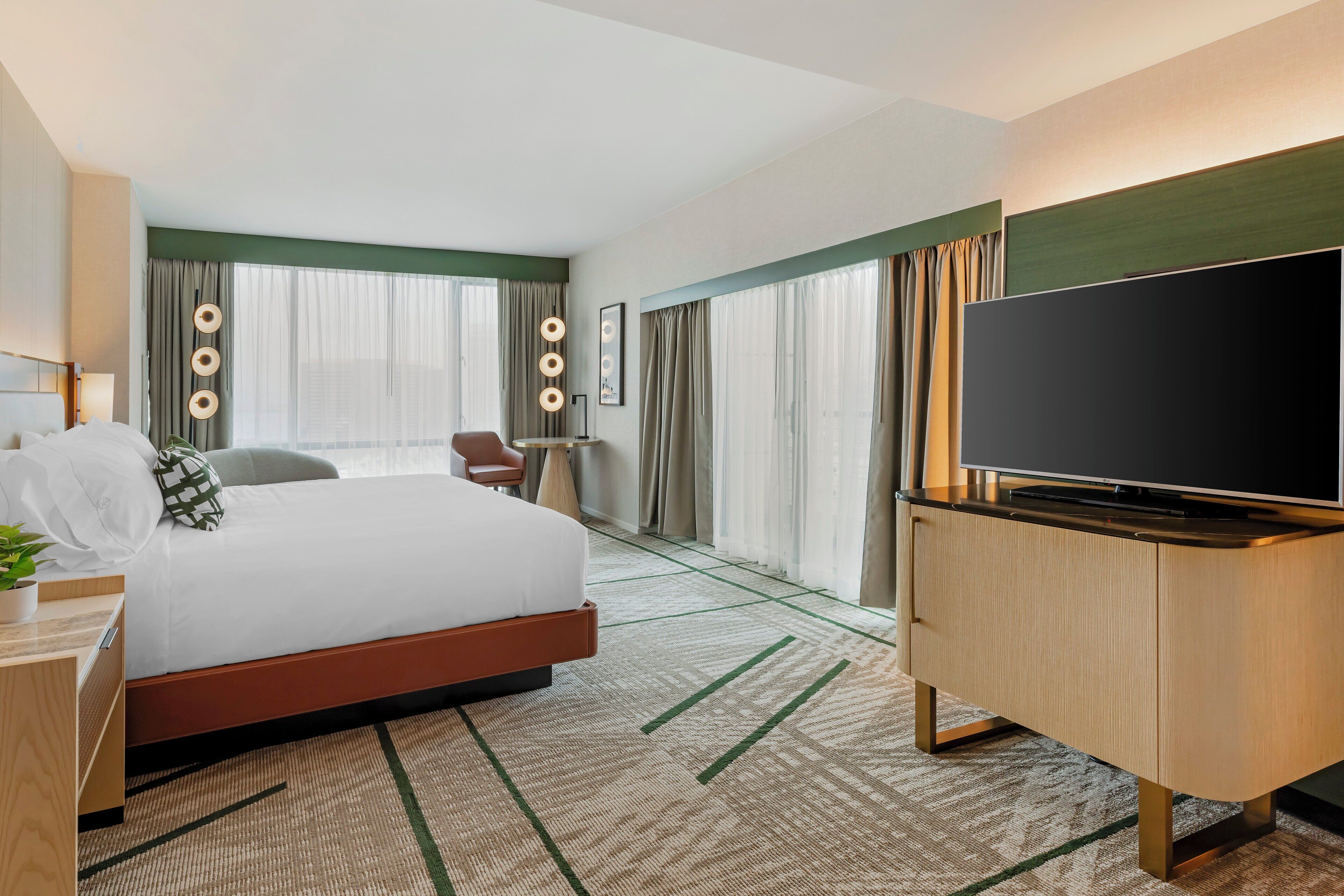 Habitación de hotel con una cama grande, un televisor de pantalla plana, un escritorio con lámpara y una silla.