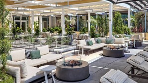 Un patio al aire libre con arreglos de asientos, incluyendo sofás, sillas y mesas redondas.