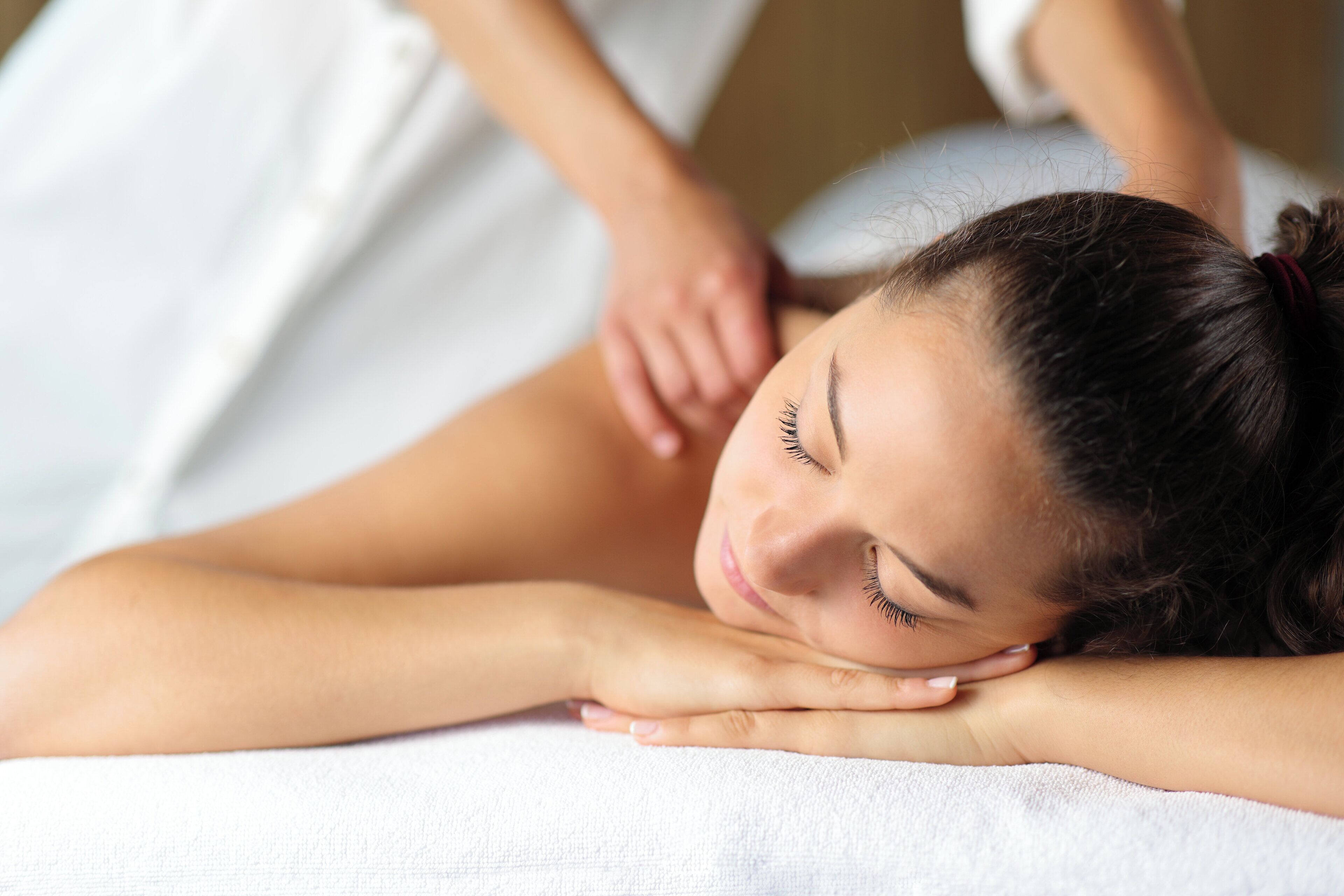 A person lying on a massage table receiving a back massage.