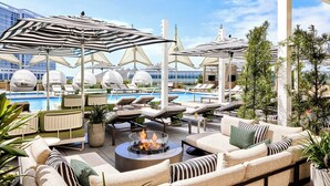 Un área de lounge en la azotea con asientos exteriores, piscina y sombrillas.