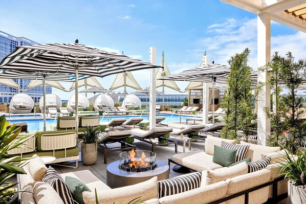 A rooftop lounge area with outdoor seating, a pool, and umbrellas.