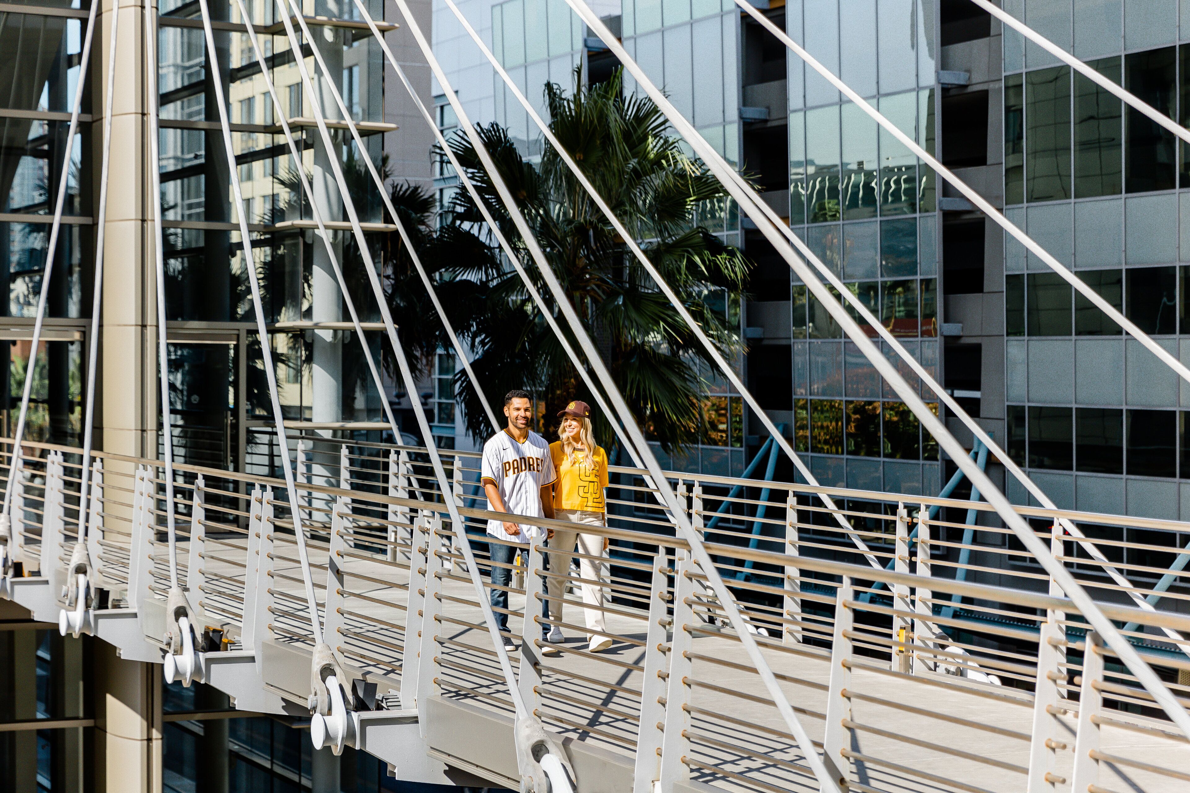 A pedestrian bridge with metal railings and a modern building in the background.