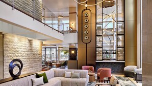 Un lobby amplio con techo alto, un sofá modular grande, varias zonas de estar y una lámpara de araña moderna.