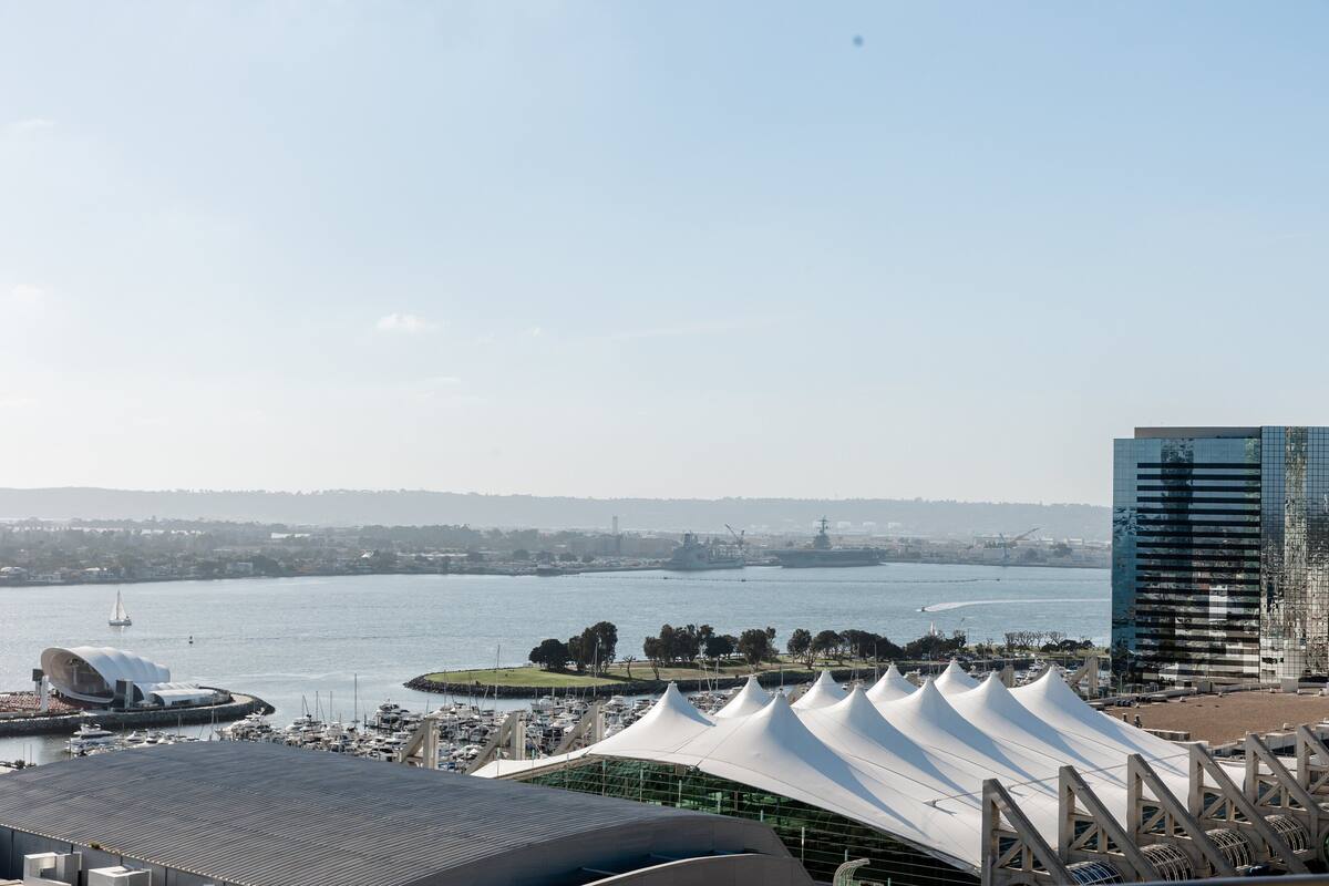 Vista al agua con un edificio moderno, un puerto deportivo y un velero.