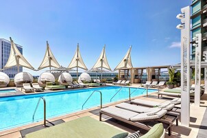 Una piscina al aire libre, camas de piscina con cargo, sombrillas