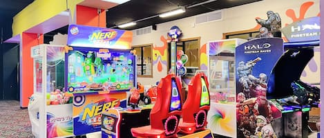 A colorful arcade area with various gaming machines, including a 'Nerf Arcade' and a 'Halo Fireteam Raven' game.