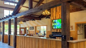 A reception area with wooden paneling, a reception desk, a chandelier, and a television screen. - The Waters Of Minocqua (Minocqua)