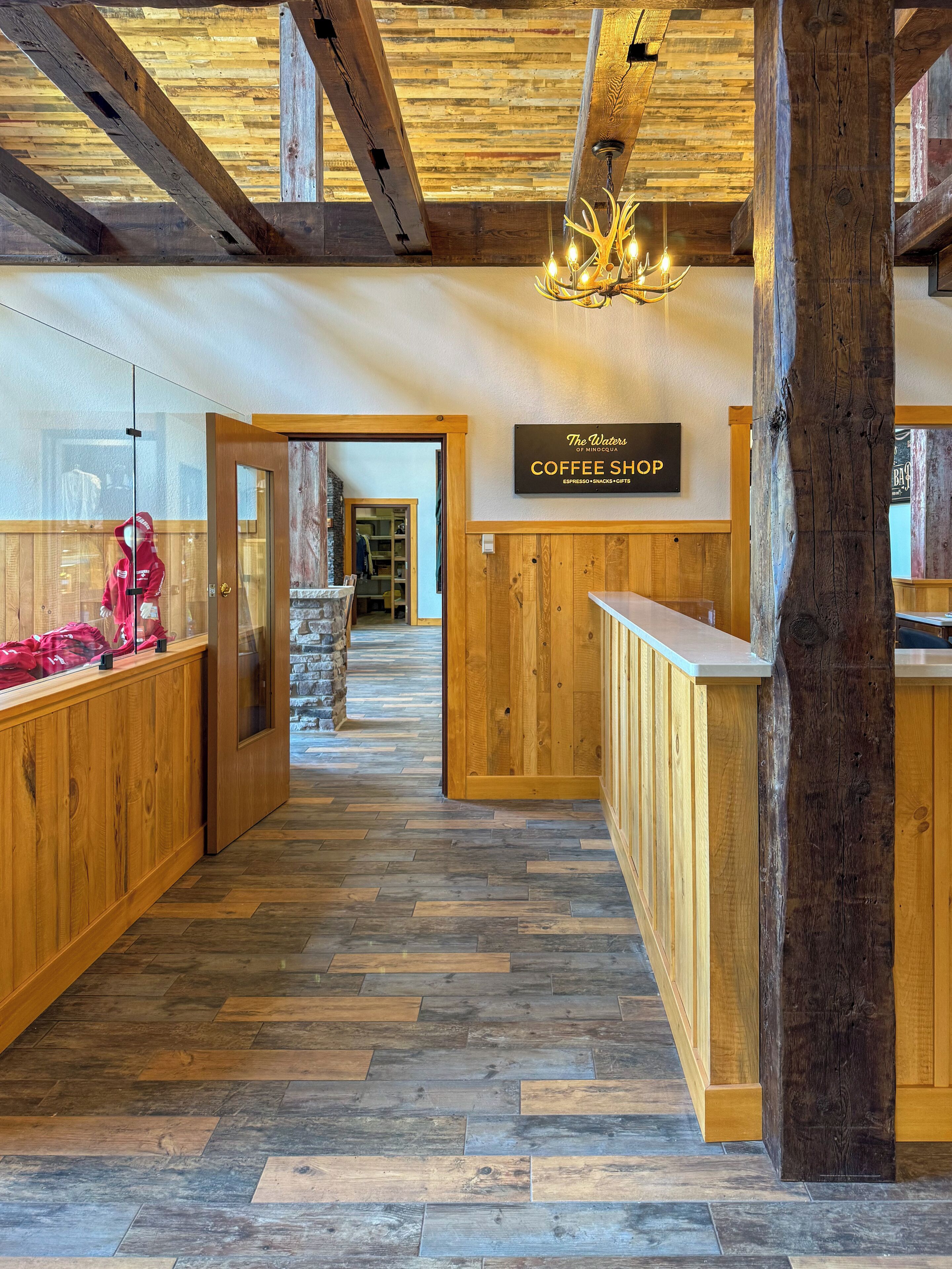 Un interno in legno con un cartello che indica 'The Waters Coffee Shop' e un pavimento a pattern a spina di pesce.