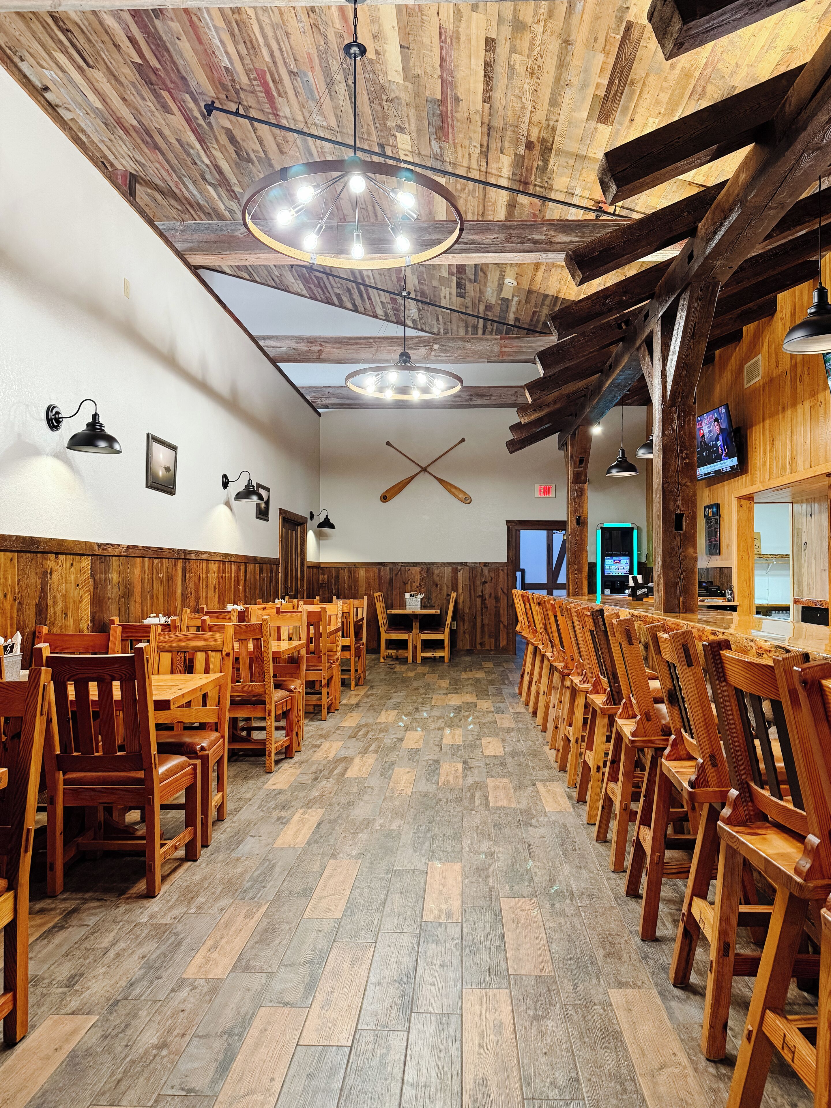 A restaurant with wooden floors, tables, and chairs arranged in rows.