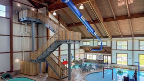 An indoor swimming pool with a wooden staircase and lounge area. - The Waters Of Minocqua (Minocqua)