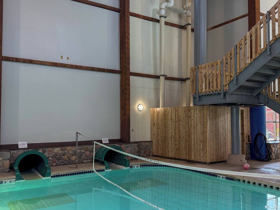 Piscina interna com deck de madeira e parede de pedra.