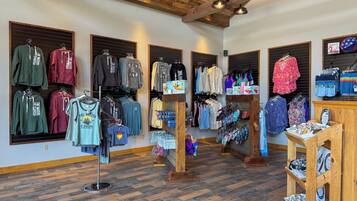 A clothing store with wooden floors and exposed beams, featuring various apparel and accessories.