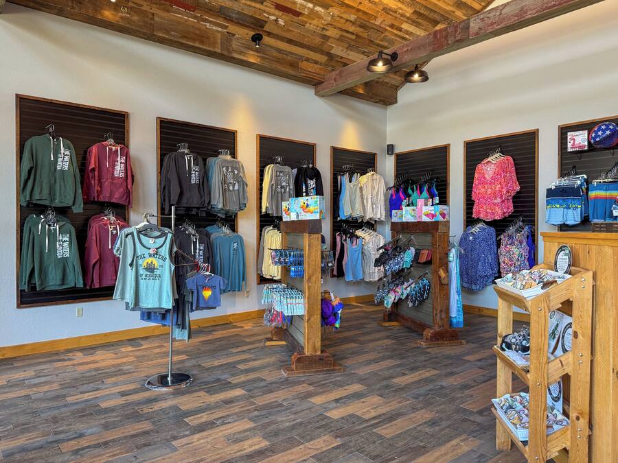 A clothing store with wooden floors and exposed beams, featuring various apparel and accessories.