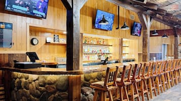 A bar area with wooden walls, stone accents, and multiple TVs.