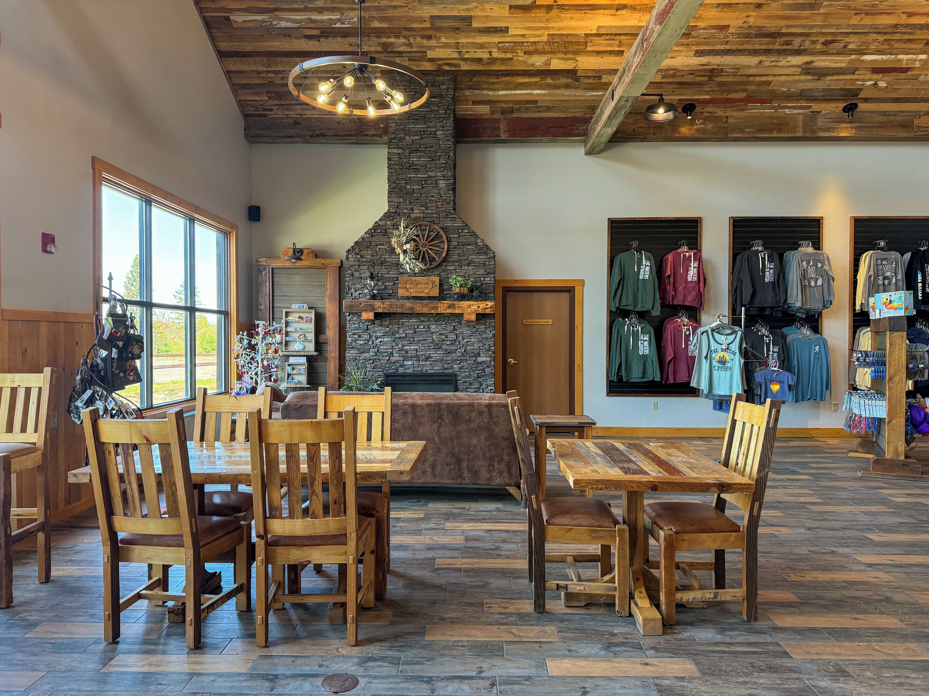A rustic interior with wooden furniture, a stone fireplace, and a clothing store.