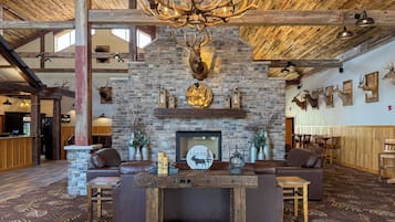 Un interior rústico con chimenea de piedra, sofás de cuero, una araña y decoración de cornamentas.