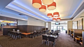 A hotel lobby with a long reception desk, multiple seating areas, and a patterned carpet.