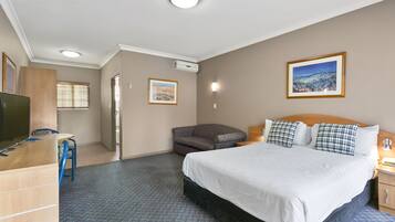 A hotel room with a bed, a desk, a chair, a sofa, and a TV.