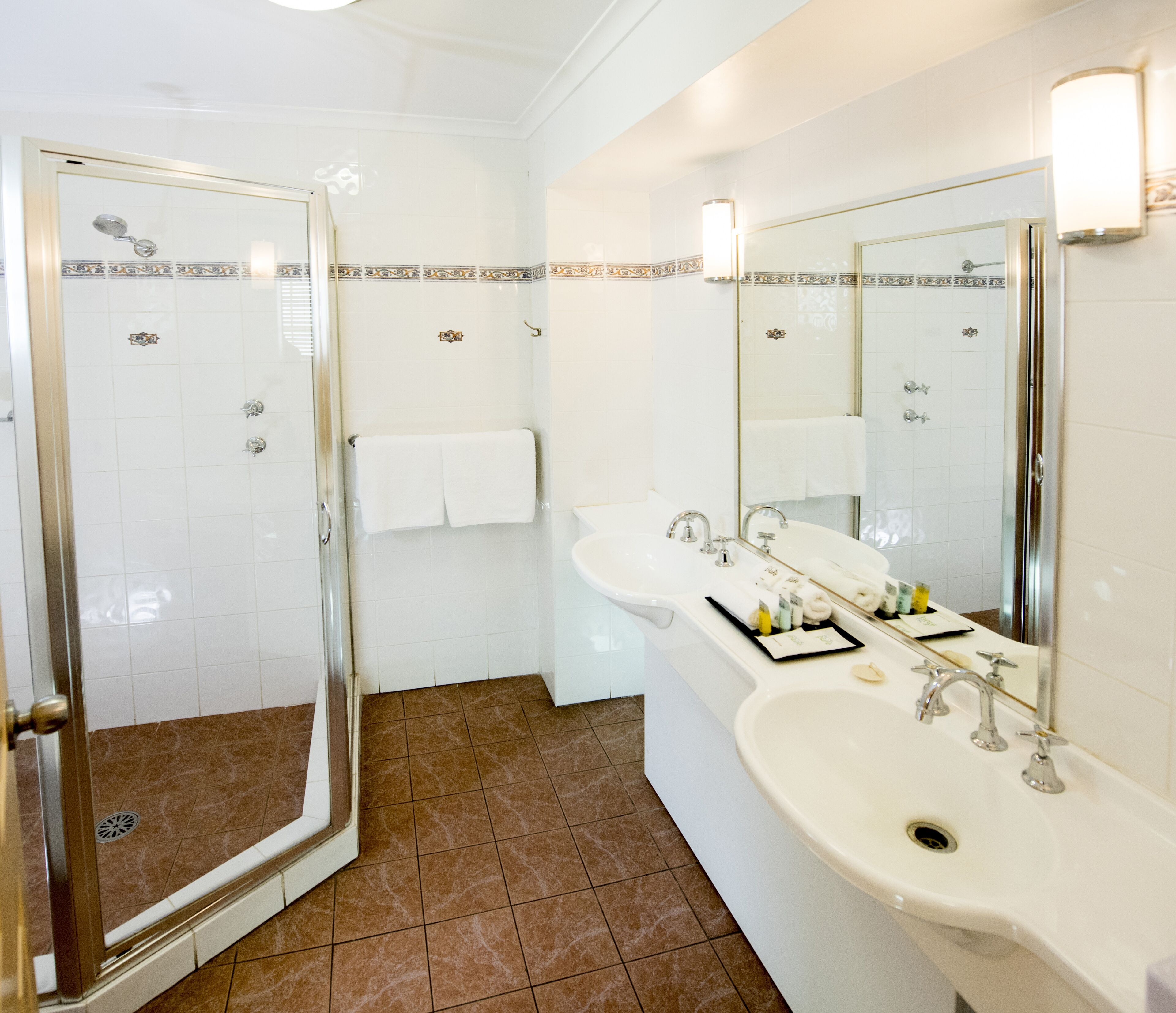 A bathroom with a glass shower door, a sink with a mirror, and a towel rack.