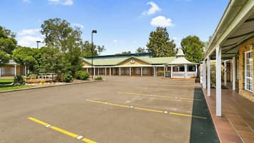 A spacious parking lot with a building featuring a green roof and a gazebo.