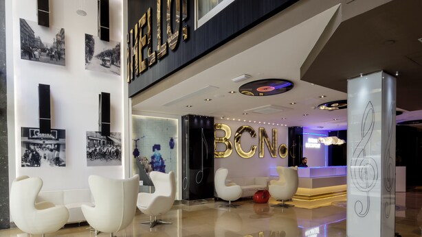 A modern lobby with a 'HELLO' sign, contemporary chairs, and a reception desk. - Evenia Rocafort (Barcelona)