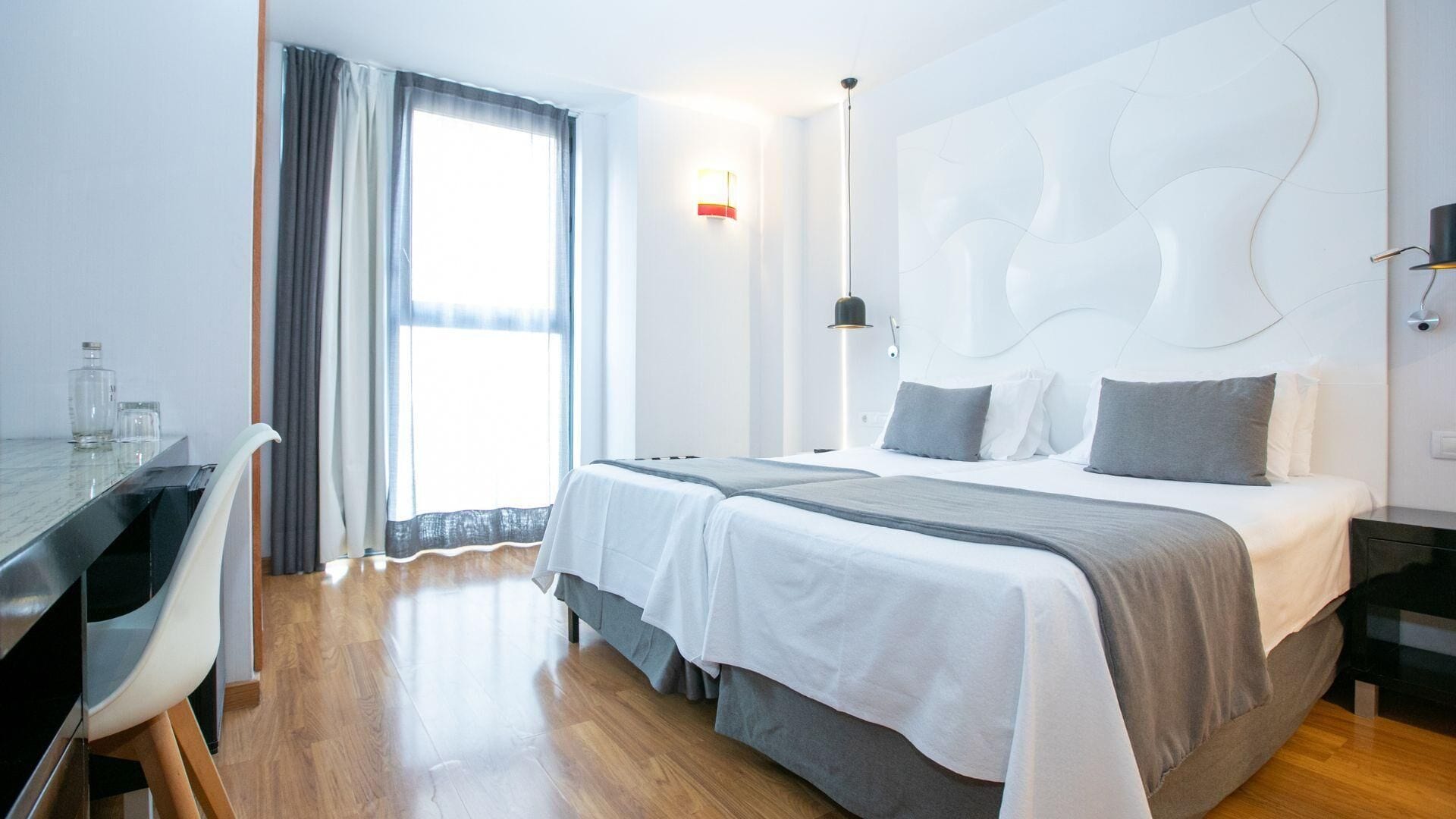 Una habitación de hotel moderna con una cama grande, un escritorio y una ventana con cortinas.