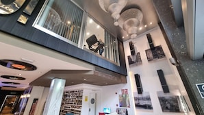 A modern interior with a mezzanine level, large windows, and a central staircase.