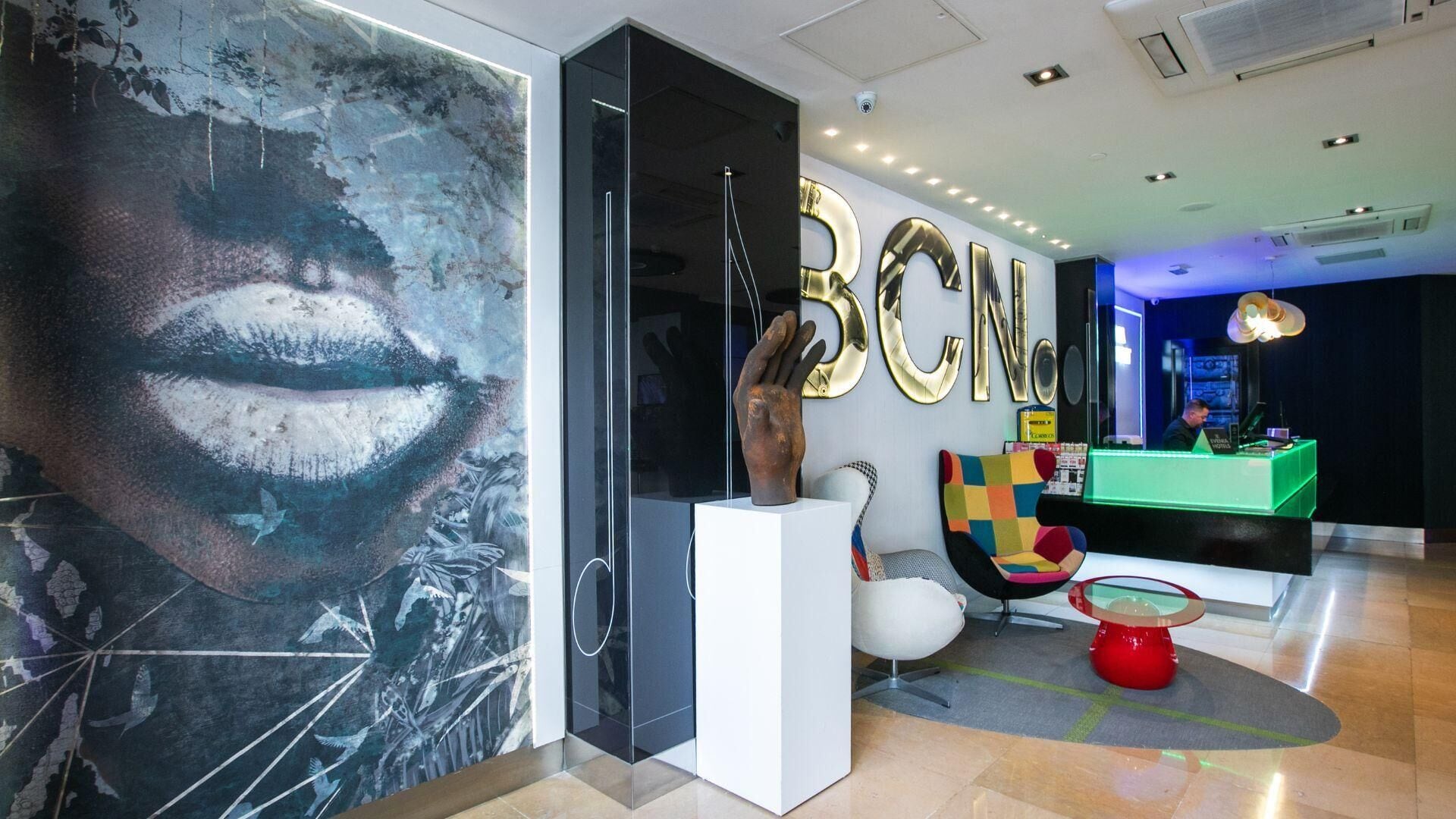 Eine moderne Lobby mit einem großen, abstrakten Kunstwerk, einem Empfangsbereich und einer farbenfrohen Lounge.