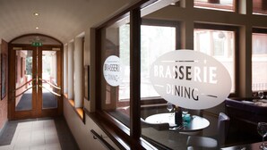A restaurant interior with a sign reading "BRASSERIE DINING" and a view of the dining area through a window. - Staindrop Hotel (Sheffield)