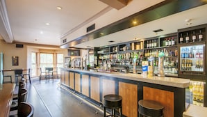 A bar area with a long counter, multiple stools, and shelves stocked with bottles. - Staindrop Hotel (Sheffield)