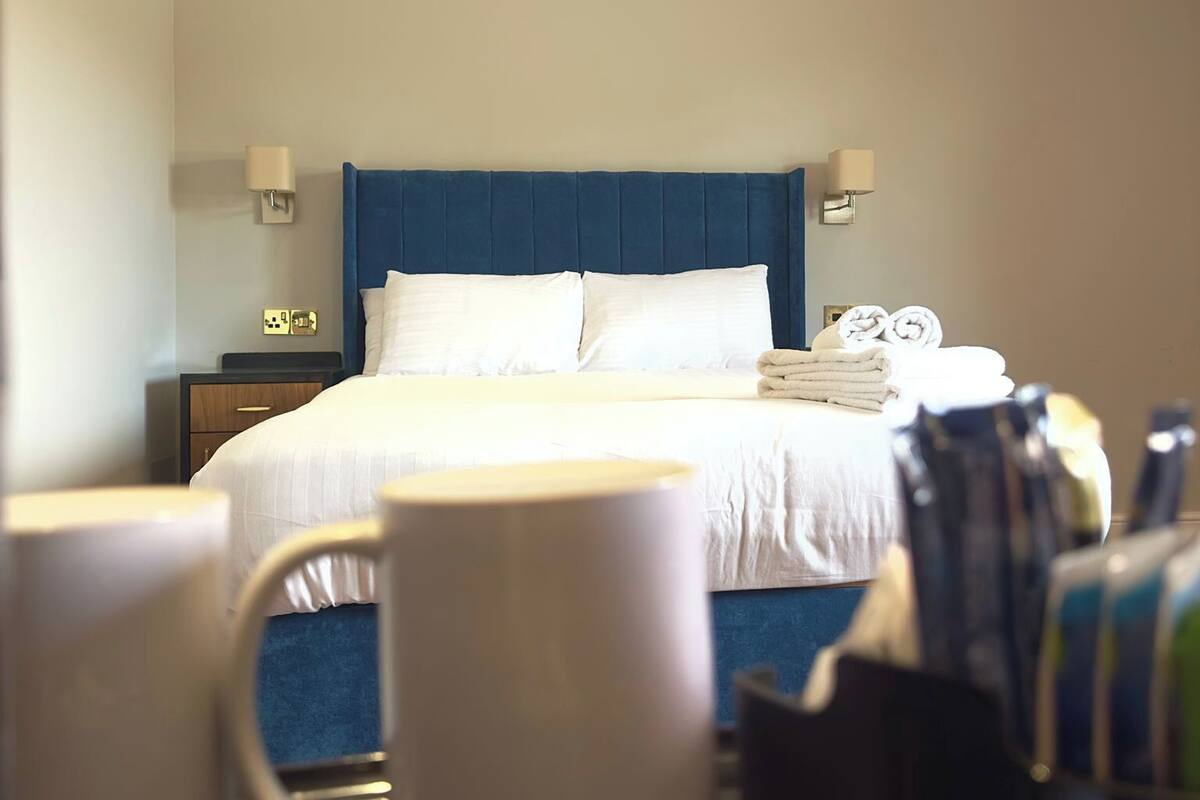 A hotel room with a bed, bedside lamps, a nightstand, a chair, and a table with toiletries.