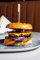 Hamburguesa con un palillo sobre un plato.